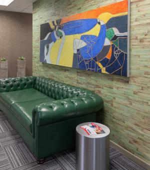Contemporary office lounge with green leather couch and modern wall art